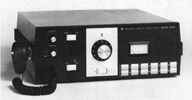 Radio transceiver with 3 knobs, 15 push buttons and meter on front and microphone hung on left side