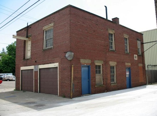 Photo of a 2 story brick building with 2 garage doors on the street side.