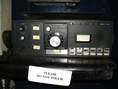 Table top Transceiver with large channel select knob, 3 other knobs, 4 rocker switches, S meter, speaker and microphone hanging on the side