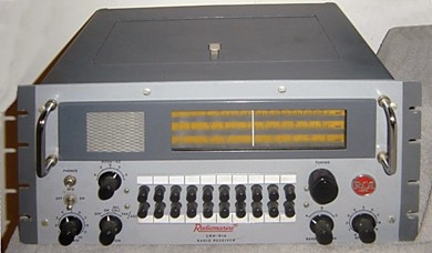 Rack-mounted radio receiver with a speaker grill, 5 small knobs,  a tuning-knob, multiple push-buttons and slide-rule dial