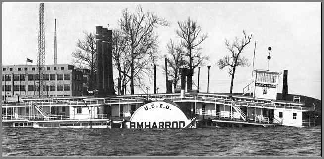 Flood scene with sunken dredge in the foreground and the USACE building and WUG2 towers in the background