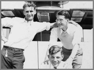 Three radio operators on deck with the bottom of one of the ship's stacks in the background.