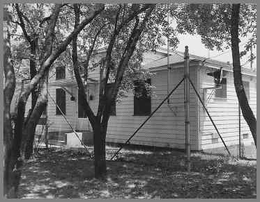 White frame WAY building partly hidden by trees